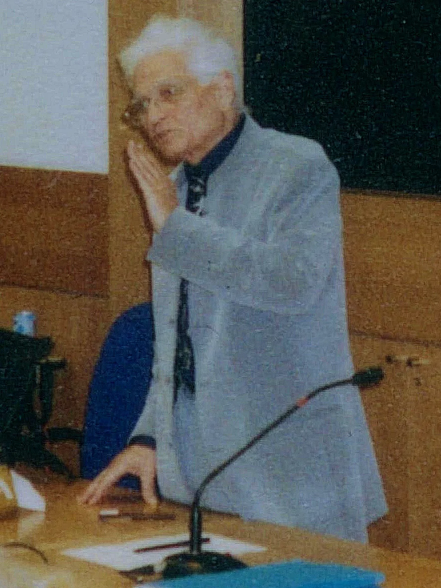 A photograph of Jacques Derrida from the 1980s: a French philosopher with white, unkempt hair, in a suit