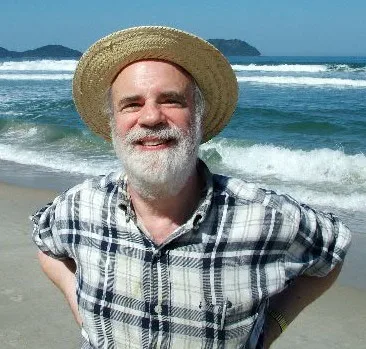 A photograph of Saul Kripke: an elderly man with glasses and white hair, speaking